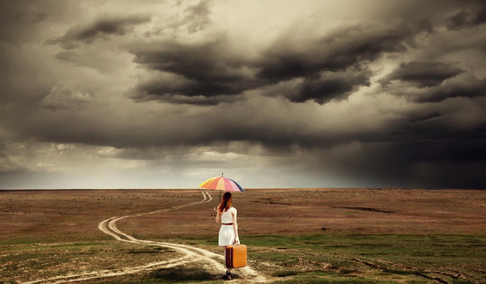 girl-with-umbrella-and-suitcase-walking-by-the-road-at-countrysi